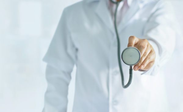 Arzt oder Ärztin hält ein Stethoskop nach vorn – Symbol für medizinische Versorgung, Gesundheitscheck und Patientenbetreuung.