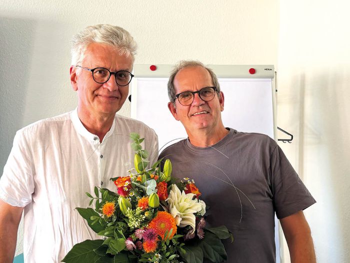 Sitzung der Ärztekammer mit zahlreichen Teilnehmern an Tischen, Vortragendem am Podium und Präsentation im Konferenzraum.