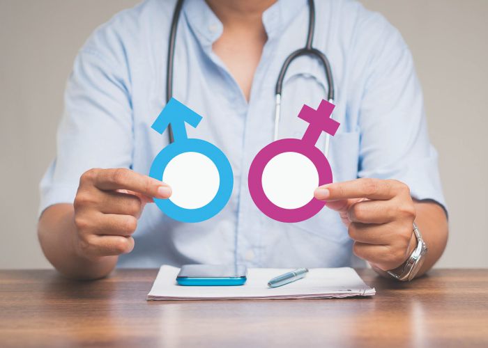 Arzt hält Symbole für Mann und Frau, Beratung zu Geschlechtergesundheit und medizinischer Aufklärung