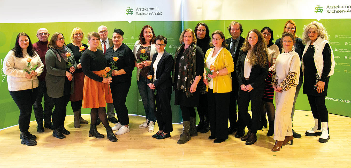 Gruppenfoto von Absolventinnen und Absolventen mit Blumen vor Kulisse der Ärztekammer Sachsen-Anhalt bei Abschlussfeier