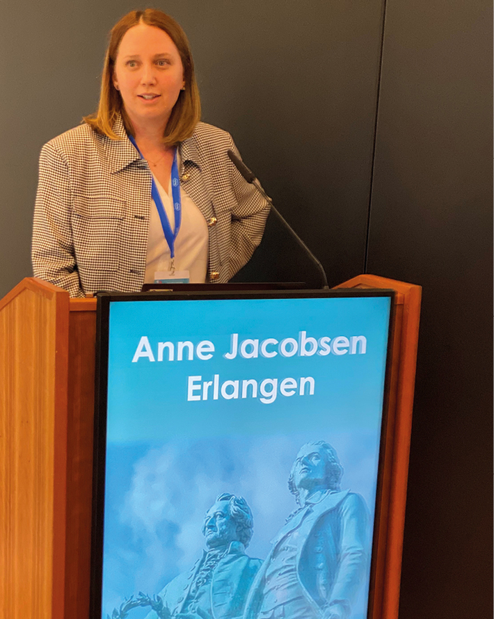 Blick in einen großen Kongresssaal mit Publikum und Podium, auf dem ein medizinischer Fachvortrag gehalten wird.