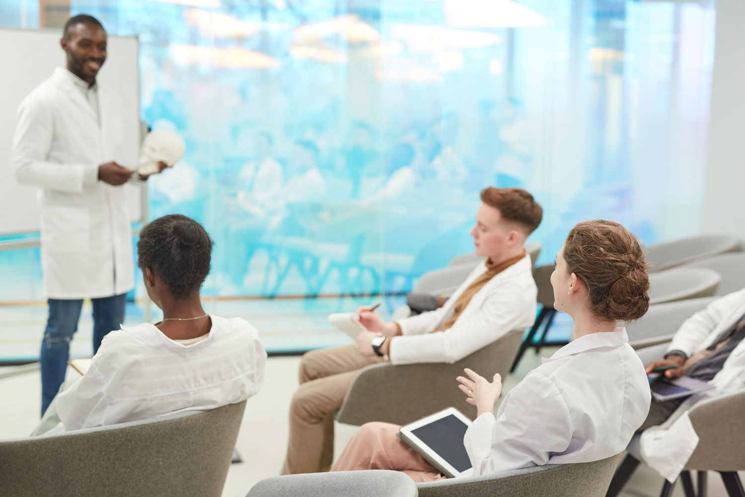 Dozent erklärt Anatomie mit Schädelmodell vor Medizinstudierenden im Seminar zur klinischen Ausbildung