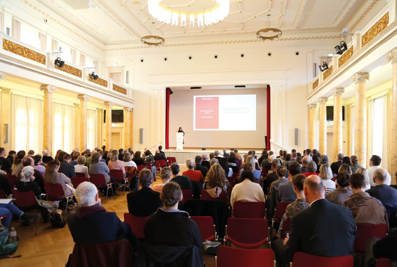 Abschlussfeier Humanmedizin: Absolventinnen und Absolventen werfen Hüte in die Luft auf der Bühne im Hörsaal