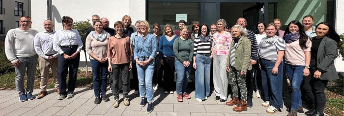 Sitzung der Ärztekammer mit zahlreichen Teilnehmern an Tischen, Vortragendem am Podium und Präsentation im Konferenzraum.