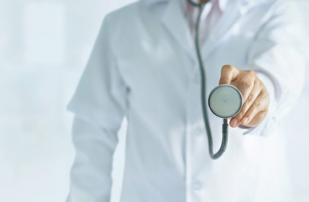 Arzt im weißen Kittel hält Stethoskop nach vorn, Symbolbild für medizinische Untersuchung und Patientenversorgung.