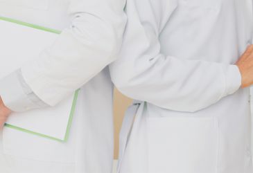 Zwei Ärzte in weißen Kitteln mit Klemmbrett und Tablet bei medizinischer Dokumentation