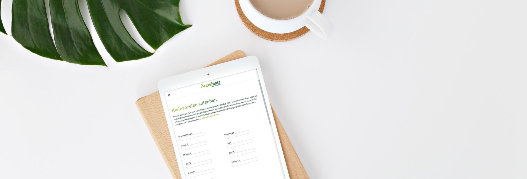 Tablet mit Online-Formular für Kleinanzeige im Ärzteblatt Sachsen-Anhalt, daneben Kaffeetasse und Blatt