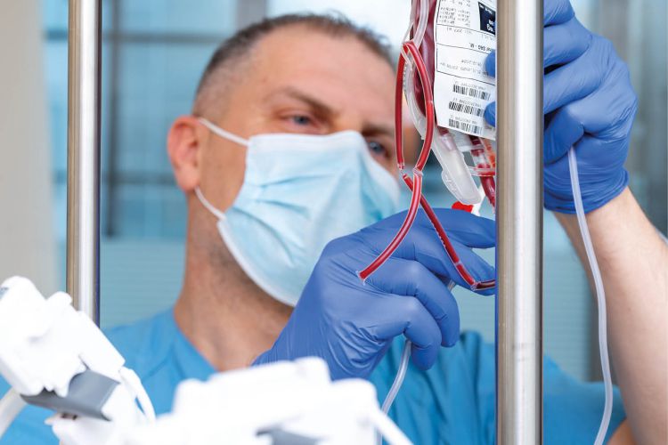 Medizinisches Personal mit Mundschutz und Handschuhen bereitet Bluttransfusion vor