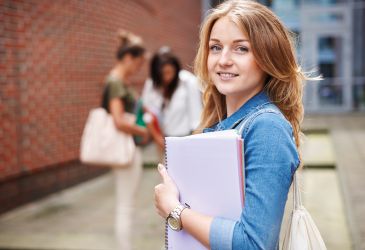 Medizinstudenten in blauen Kitteln lernen gemeinsam mit Tablet, Laptop und Unterlagen in der Ausbildung.