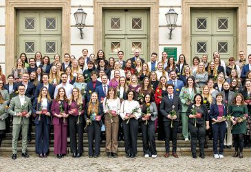 Gruppenfoto von Absolventen einer medizinischen Ausbildung mit Urkunden bei feierlicher Übergabe.