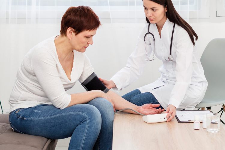Ärztin misst Blutdruck einer Patientin im Gespräch – medizinische Untersuchung in moderner Praxisumgebung.Bluttransfusion vor