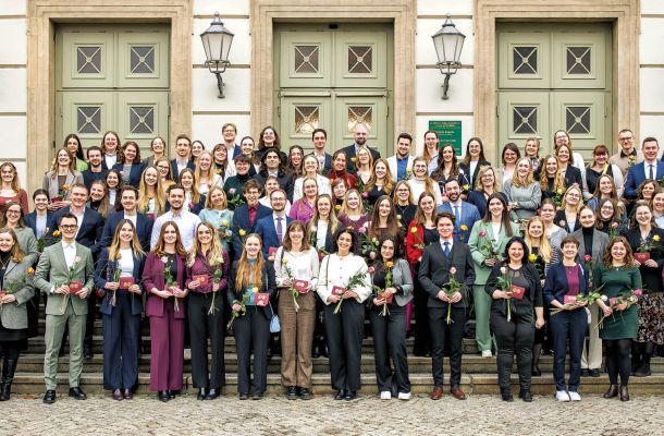 Gruppenfoto von Absolventen einer medizinischen Ausbildung mit Urkunden bei feierlicher Übergabe.