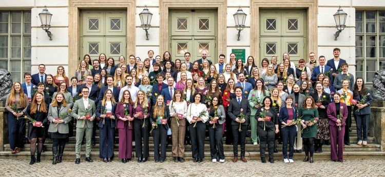Gruppenfoto von Absolventen einer medizinischen Ausbildung mit Urkunden bei feierlicher Übergabe.