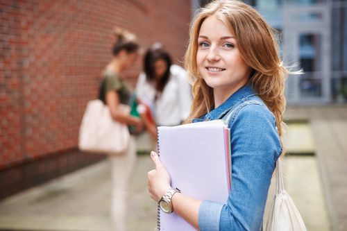 Medizinstudenten in blauen Kitteln lernen gemeinsam mit Tablet, Laptop und Unterlagen in der Ausbildung.
