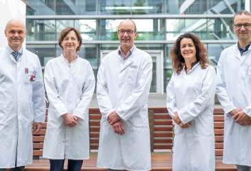 Ärzteteam im weißen Kittel vor Klinikgebäude, Experten des Sarkomzentrums Halle für interdisziplinäre Tumorbehandlung.