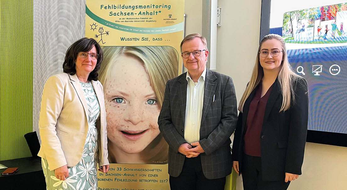 Vertreter des Fehlbildungsmonitorings Sachsen-Anhalt vor Infotafel bei einer medizinischen Veranstaltung.