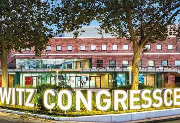 Beleuchteter Eingang des Carlowitz Congresscenters am Abend, modernes Gebäude mit großer Leuchtschrift.