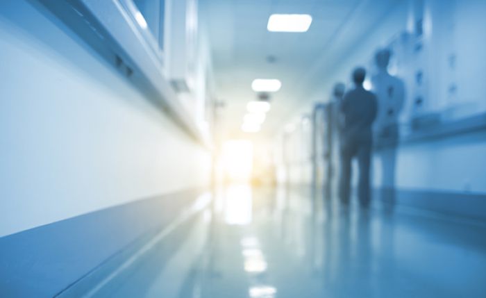 Moderner Krankenhausflur mit medizinischem Personal im Hintergrund, Symbol für Gesundheitsversorgung und Klinikalltag.