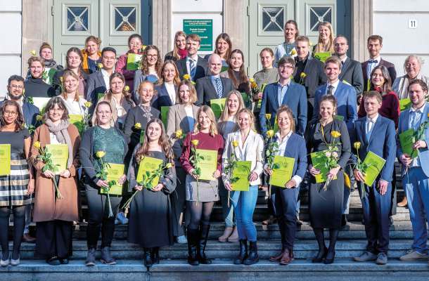 Gruppenfoto von Absolventen einer medizinischen Ausbildung mit Urkunden bei feierlicher Übergabe.