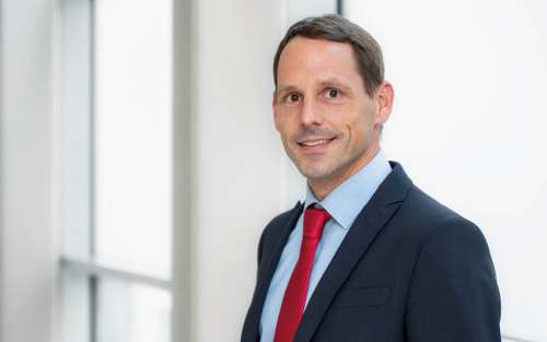 Arzt im weißen Kittel mit Stethoskop über der Schulter, Symbolbild für medizinische Versorgung und Patientenbetreuung.