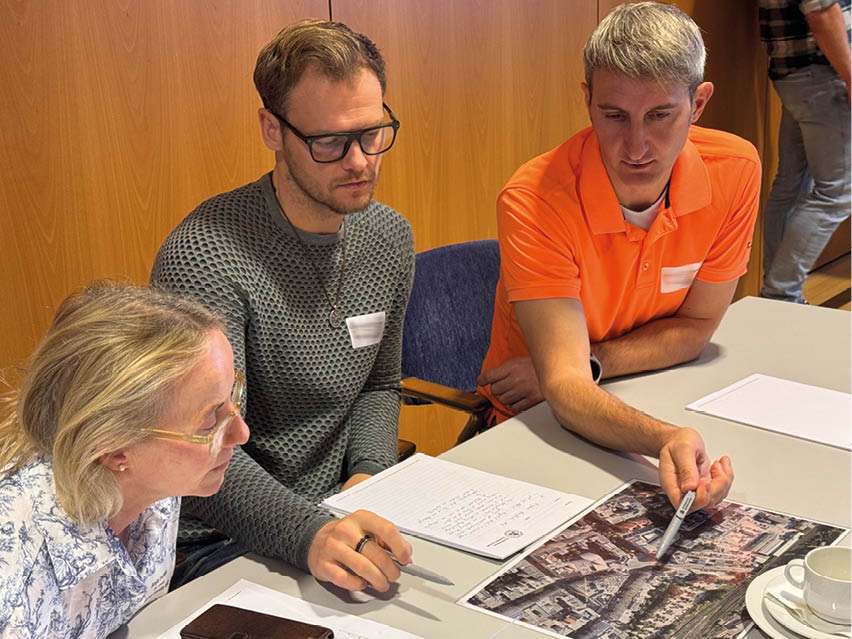 Teilnehmer einer Fortbildung analysieren gemeinsam eine Luftaufnahme und besprechen Einsatz- und Entscheidungsabläufe.