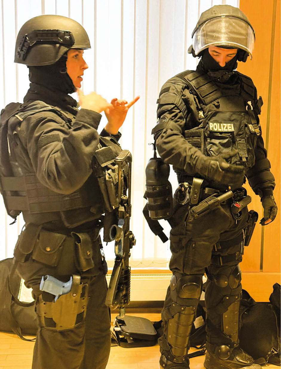 Polizeibeamte in Schutz- und Einsatzausrüstung erläutern Ausrüstung und Vorgehen im Rahmen einer medizinisch-polizeilichen Fortbildung.