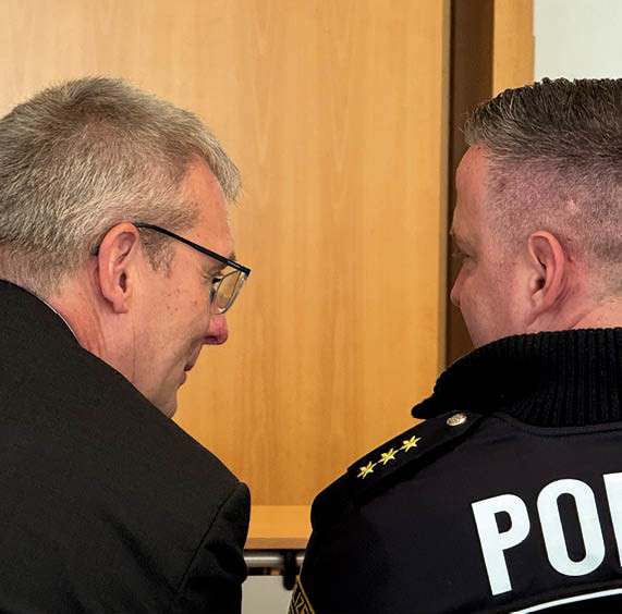 Gespräch zwischen einem Mediziner und einem Polizeibeamten im Rahmen einer Fachveranstaltung zu interdisziplinärer Zusammenarbeit.