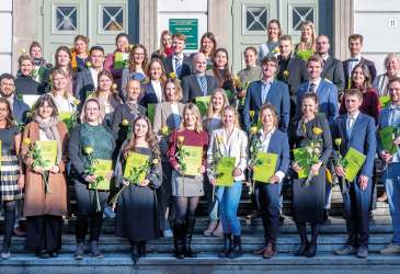 Gruppenfoto von Absolventen einer medizinischen Ausbildung mit Urkunden bei feierlicher Übergabe.