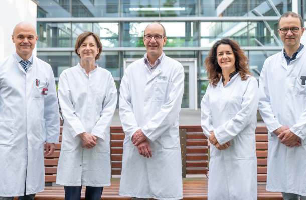 Ärzteteam im weißen Kittel vor Klinikgebäude, Experten des Sarkomzentrums Halle für interdisziplinäre Tumorbehandlung.