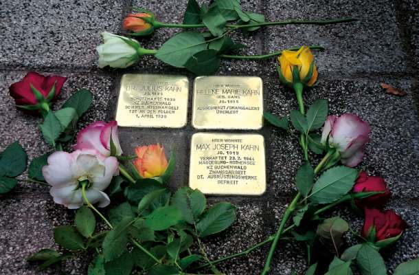 Stolpersteine mit Rosen als Gedenken an Opfer des Nationalsozialismus – Symbol für Erinnerung und Mahnung.