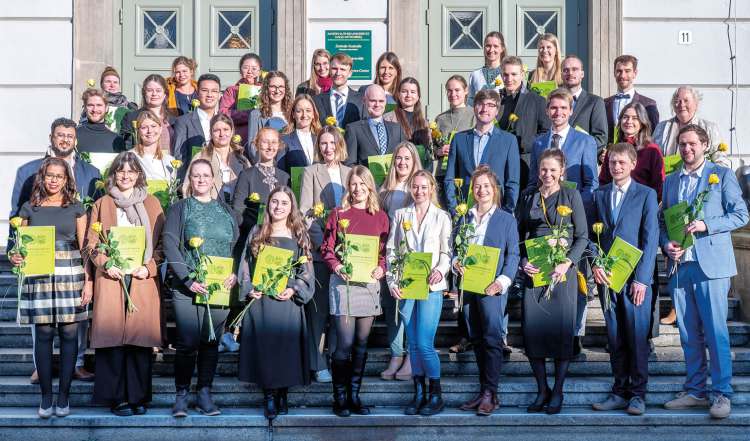 Gruppenfoto von Absolventen einer medizinischen Ausbildung mit Urkunden bei feierlicher Übergabe.