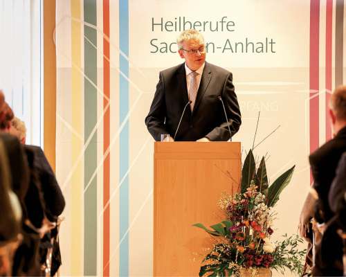 Redebeitrag bei einer Veranstaltung der Heilberufe Sachsen-Anhalt: Referent spricht am Pult vor Fachpublikum.